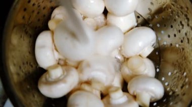 Mantar yıkıyorum. Bir kevgirde taze şampiyonların üzerine su dökülür. Yukarıdan görüntüle.