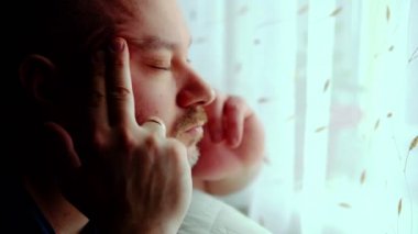 Orta yaşlı bir adam şakaklarını ovar. Yakın plan. Orta yaş krizi, baş ağrısı, tükenme sendromu konsepti.