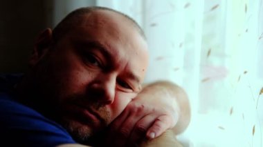 Orta yaşlı bir adam düşünceli ve üzgün bir şekilde bir odada oturur. Kameraya bakıyor. Yanık Sendromu. Orta yaş krizi.