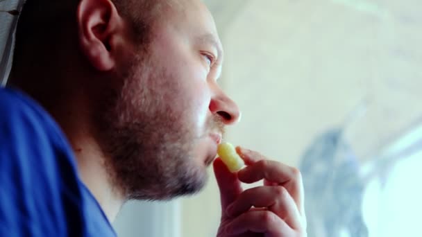 Ένας Άνθρωπος Τρώει Απερίσκεπτα Και Κοιτάζει Προσεκτικά Έξω Από Παράθυρο — Αρχείο Βίντεο