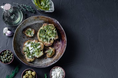 Baharatlı karnabahar bifteği, chimichurri sosu, badem gevreği. Kapari, zeytin, otlar, yan yana. Karanlık arka plan. Vejetaryen yemeği. Kopyalama. Renkli.