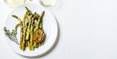 Peynirli kuşkonmaz, otlar ve limonlu baharatlar beyaz tabakta. Beyaz arka plan. Vejetaryen yemeği. Sağlıklı yemek..