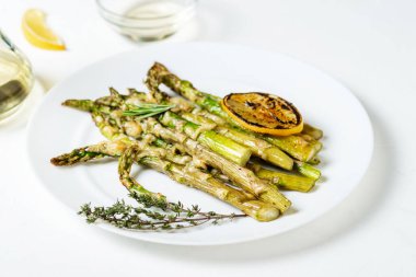 Peynirli kuşkonmaz, otlar ve limonlu baharatlar beyaz tabakta. Beyaz arka plan. Vejetaryen yemeği. Sağlıklı yemek..