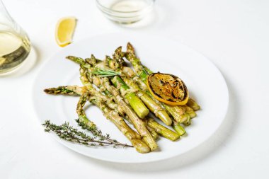 Peynirli kuşkonmaz, otlar ve limonlu baharatlar beyaz tabakta. Beyaz arka plan. Vejetaryen yemeği. Sağlıklı yemek..