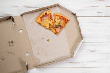 Karton bir kutuda pizza parçaları. Beyaz ahşap arka plan. Yemek konsepti. Yukarıdan görüntüle.