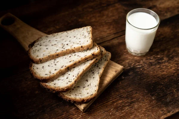 Κομμάτια Ψωμί Σπόρους Και Ένα Ποτήρι Γάλα Σκούρο Ξύλινο Φόντο — Φωτογραφία Αρχείου