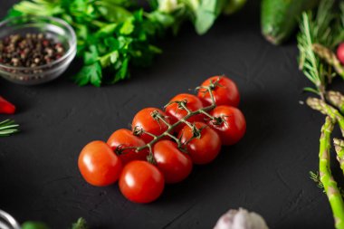 Bir dal vişneli domates. Karanlık arka plan. Çeşitli sebzeler. Vejetaryen yemeği. Çiğ gıda diyeti.