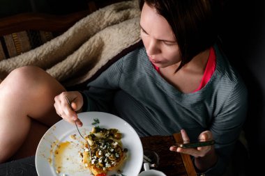 Kadın, chimichurri soslu fırında karnabahar bifteği, badem gevreği ve kapari yiyor. Vejetaryen yemeği. Alternatif lezzetli yemekler..