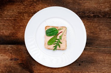 Vejetaryen sandviçi. Kremalı tost ve çeşitli yenilebilir salata yaprakları. Beyaz plaka, koyu ahşap arka plan. Sağlıklı beslenme. Yiyecek konsepti.