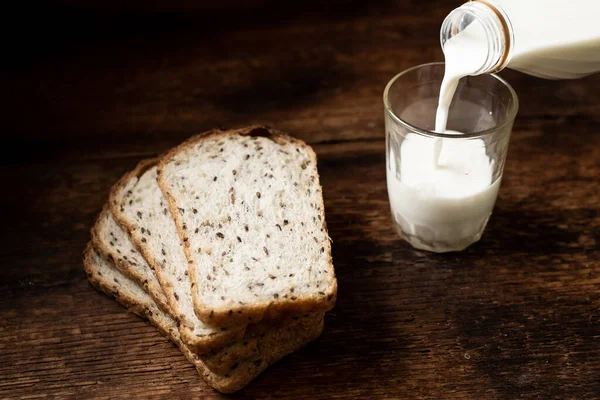Pezzi Pane Con Semi Latte Vengono Versati Bicchiere Fondo Legno — Foto Stock