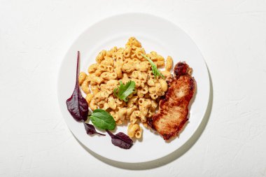 Peynir soslu makarna, doğranmış et ve marul. Minimalist gıda tasarımı. Beyaz arkaplan.