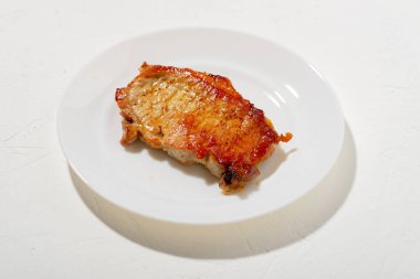 Beyaz tabakta bir parça kızarmış et. Kötü yağlı yemek. Beyaz arka plan. Tereyağında kızartılmış bir parça domuz eti. minimalizm