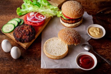 Ev yapımı hamburger ya da çizburger. Klasik bir hamburger için farklı malzemeler. Ahşap arka plan. Yiyecek konsepti.