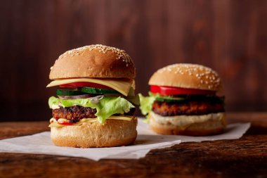 Ahşap arka planda iki hamburger. Büyük ve küçük çizburger. Hamburger günü..