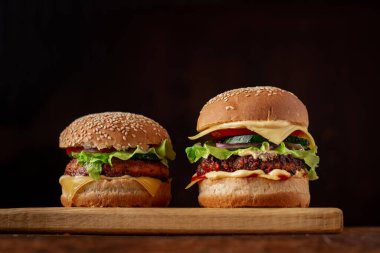 Ahşap arka planda iki hamburger. Büyük ve küçük çizburger. Hamburger günü..