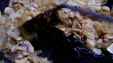 Tavada soğan olan kızarmış mantarlar. Yakın plan. Spatula hareketleniyor..