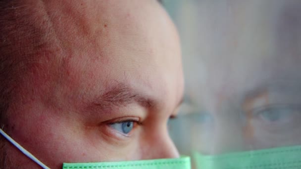 Ein Mann Mit Medizinischer Maske Schaut Aus Dem Fenster Ein — Stockvideo