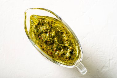 Beyaz arka planda soslu Chimichurri sosu. Arjantin vejetaryen sosu zeytinyağı, kekik, maydanoz.