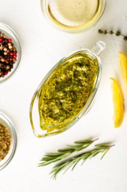 Beyaz arka planda soslu Chimichurri sosu. Macro vuruldu. Zeytin yağı, kekik otu ve maydanozdan yapılmış Arjantin vejetaryen sosu. Üst görünüm.
