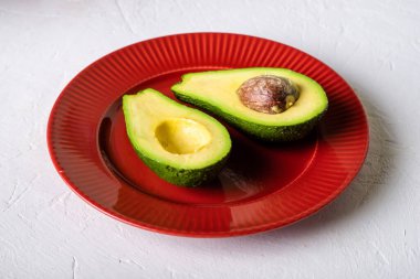 Kırmızı tabakta dilimlenmiş avokado. Beyaz arka plan. Minimalizm.