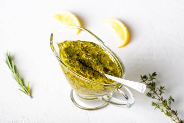 Beyaz arka planda soslu Chimichurri sosu. Arjantin vejetaryen sosu zeytinyağı, kekik, maydanoz.