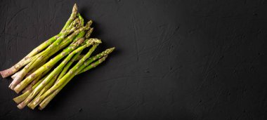 Çiğ kuşkonmaz sapları. Karanlık arka plan. Metin için yer.