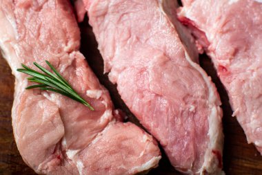 Kesme tahtasında çiğ et. Beyaz arka plan. Domuz eti pişirme hazırlığı. Yakınlarda çeşitli baharatlar ve baharatlar var..