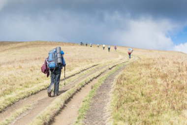 Sırt çantalı bir grup insan dağlarda yürüyüş yapıyor..