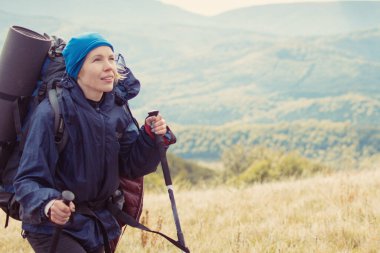 Dağlarda yürüyüş yapan büyük sırt çantalı bir kadın..
