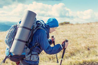 Dağlarda yürüyüş yapan büyük sırt çantalı bir kadın..