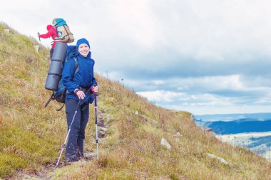 Dağlarda yürüyüş yapan büyük sırt çantalı bir kadın..