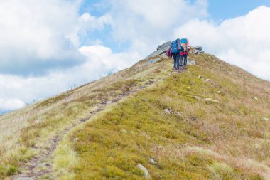 Sırt çantalı iki kişi dağlarda yürüyüş yapıyor..