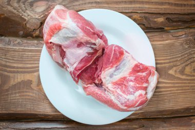 Tahta arka planda beyaz tabakta taze çiğ domuz eti..
