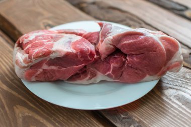 Tahta arka planda beyaz tabakta taze çiğ domuz eti..