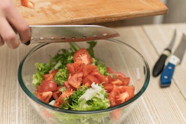 Bir kadın salata kasesine doğranmış domates koyar..