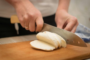 Kadın kesme tahtasıyla peynir dilimliyor..