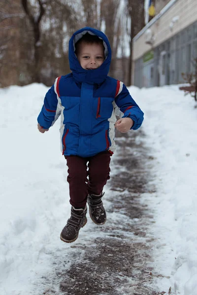 Malý Chlapec Modré Zimní Bundě Skáče Ulici Sněhem — Stock fotografie