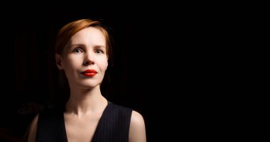 Siyah arka planda kırmızı dudaklı bir kadın kameraya bakar. Orta yaşlı, 40 yaşında, çekici bir kadın. Pankart. Metin için yer.