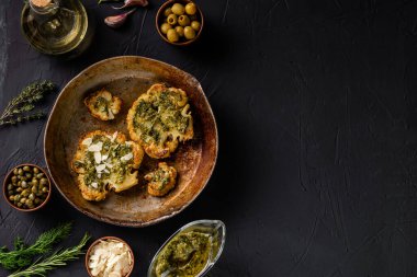 Baharatlı karnabahar bifteği, chimichurri sosu, badem gevreği. Kapari, zeytin, otlar, yan yana. Karanlık arka plan. Vejetaryen yemeği. Kopyalama alanı.