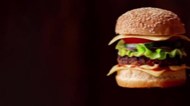 Bir sıra taze lezzetli hamburger koyu bir arka planda tutulur. Hamburger günü. Üretim, hamburgerler konsepti.