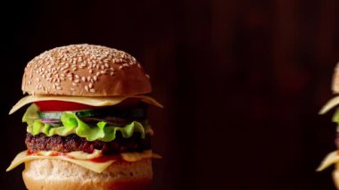 Hamburger günü. Taze lezzetli hamburgerler ortaya çıkar ve hareket eder. Karanlık arka plan. Canlandırma.