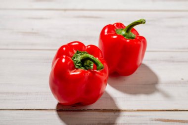 Ahşap arka planda iki kırmızı tatlı biber. Hafif arkaplan. Yiyecek, vejetaryen konsepti.