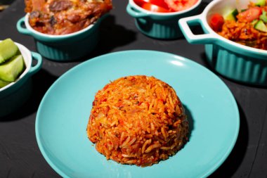 Tabakta jollof pilav. Domatesli pilav, soğan, baharat. Geleneksel Nijerya yemekleri. Koyu arkaplan.