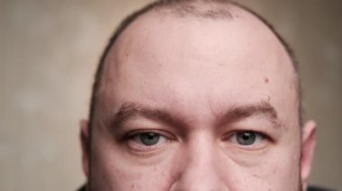Bir adam kameraya yakından bakıyor. Yüzün üst yarısı. Orta yaşlı bir adam, kırk yaşında..