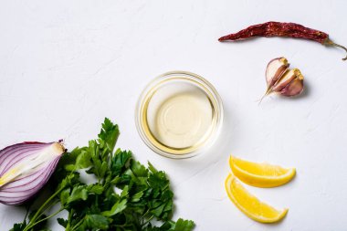Sos hazırlığı. Limon, zeytinyağı, maydanoz, kişniş, beyaz arka planda sarımsak..