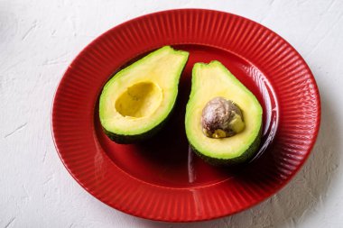 Kırmızı tabakta dilimlenmiş avokado. Beyaz arka plan. Minimalizm.