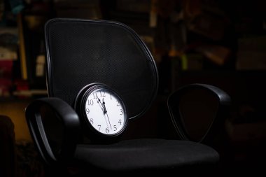 Teslim tarihi konsepti, zaman yönetimi. Siyah arka planda bir ofis sandalyesindeki saat.