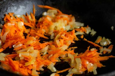 Yakın planda havuçlu kızarmış soğan. Yemek pişirmek için malzemelerin hazırlanması.