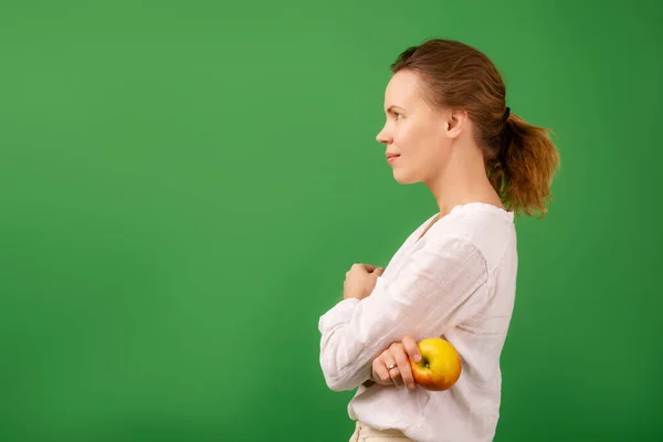 Доросла Красива Жінка Білій Сорочці Тримає Свіже Яблуко Зеленому Тлі — стокове фото