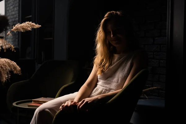 Uma Jovem Mulher Vestido Branco Senta Pensativamente Uma Poltrona Quarto — Fotografia de Stock